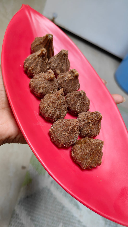 Red plate with brown textured items held by a hand on a blurred background